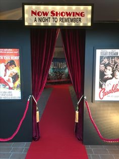 a red carpeted hallway leading to a movie theater with posters on the walls and curtains