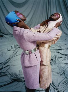 two black women with hats on their heads, one holding the other's head