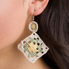 a close up of a person wearing earrings with crochet designs on them and one earring