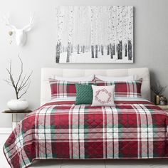 a red and green plaid comforter set on a bed in a room with white walls