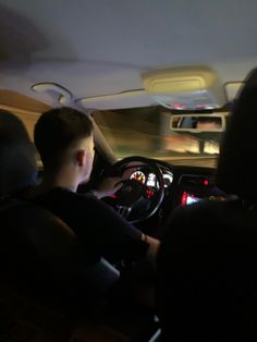 a young man driving a car at night