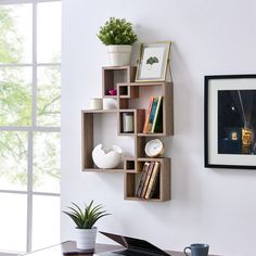 a laptop computer sitting on top of a wooden shelf next to a potted plant