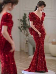 a woman in a red dress standing next to another woman wearing a red evening gown