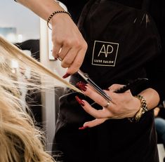 a woman is getting her hair done by another person at a beauty salon with red nail polish