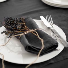 a black table cloth with white plates and silverware on it, along with napkins