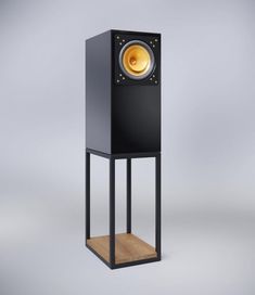 a black speaker stands on top of a wooden stand with an orange light in the center