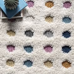 a white rug with multicolored circles on it and a blue book next to it