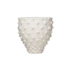 a white ceramic vase with small dots on it's rim and bottom, sitting on a white surface