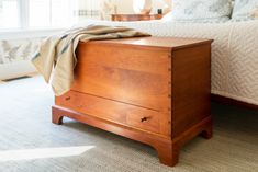 a bed sitting next to a wooden dresser on top of a carpeted floor in front of a window