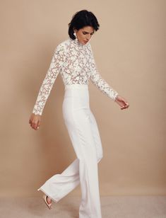 a woman in white pants and lace top posing for the camera with her hand on her hip