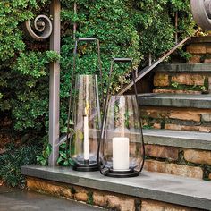 two clear glass vases sitting on top of a set of steps next to a candle