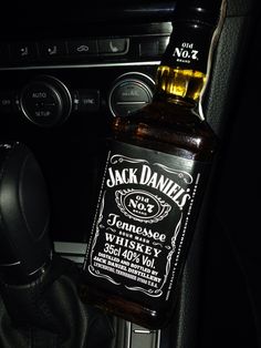 jack daniels whiskey bottle sitting in the center console of a car with steering wheel controls