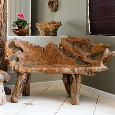 a wooden bench sitting in front of a mirror on top of a tiled floor next to a potted plant