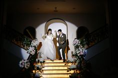 a bride and groom are standing on the stairs at their wedding reception in front of an archway