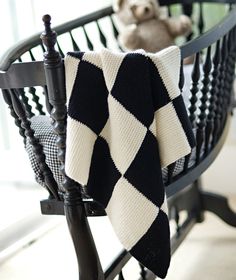 a teddy bear is sitting on a rocking chair with a black and white checkered blanket