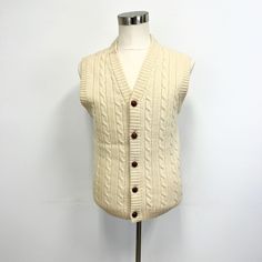 "Vintage cable knit sweater vest featuring; a v neck buttons down the front with embossed \"leather look\" buttons  this has a cable knit pattern on the front and is smooth on the back ribbed at the neck, armholes, and bottom Of a mid weight, 100% wool knit in ecru. Labeled \"Gant, The Rugger\" it has no size tag, measurements when laid out flat are; 20 inches from pit to pit 17 inches across the bottom 27 inches from nape of neck to bottom In good, preworn, vintage condition with stains, or fun Classic Cable Knit Sweater Vest For Fall, Wool Sweater Vest With Buttons For Fall, Classic Sweater Vest With Button Closure For Fall, Classic Winter Sweater Vest With Button Closure, Classic Beige Knit Sweater Vest, Vintage Button Sweater Vest For Winter, Classic Beige Wool Sweater Vest, V-neck Sweater Vest With Buttons For Winter, Knit V-neck Sweater Vest With Buttons