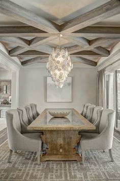 a dining room table with chairs and a chandelier hanging from it's ceiling