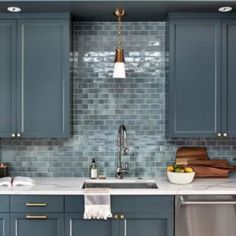 a kitchen with blue cabinets and white counter tops, stainless steel dishwasher and sink