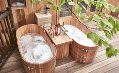 two wooden tubs sitting on top of a wooden deck next to each other with soap in them