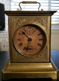 an antique brass clock with roman numerals on the face is sitting on a table