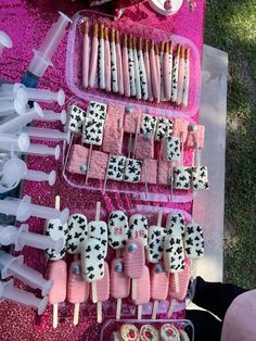 a table topped with lots of pink and white cake pops next to donuts on sticks