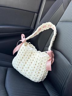 a crocheted purse sitting in the back seat of a car with a pink bow