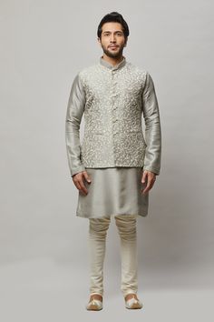 Cotton Linen blended kurta with floral ivory thread & gold sequence intertwined embroidered vest plus ivory churidar. The cotton-linen blend makes it one of our lightest and most breathable kurtas. Crafted with a collar neckline, full sleeves, and front button closure. Occasion: Can be worn to events like Sangeet, Mehendi, & Wedding WASH CARE INSTRUCTIONS - Please Dry clean only when it is applicable. Slight color variation is possible due to digital photography. Festive Fitted Off White Nehru Jacket, Festive Raw Silk Nehru Jacket For Spring, Spring Festive Raw Silk Nehru Jacket, Spring Wedding Chanderi Bandhgala, Fitted Chanderi Sherwani For Spring, Spring Wedding Bandhgala In Chanderi, Spring Wedding Cotton Silk Bandhgala, Spring Fitted Chanderi Sherwani, Spring Wedding Sherwani In Raw Silk