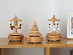 three small wooden figurines on top of a table next to a framed photo