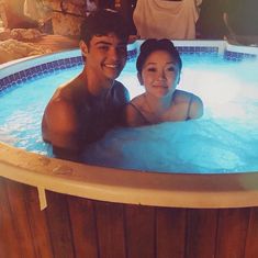 a man and woman sitting in a hot tub smiling at the camera while they pose for a photo