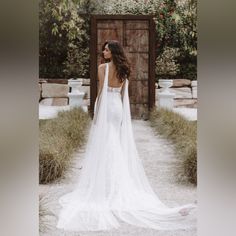 a woman in a white wedding dress standing on a path with her back to the camera