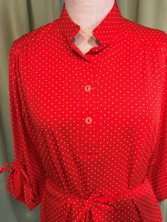 "This is an adorable vintage, blouse from the 1960s or 70s. No labels or tags. The bust measures 40\" with measurements below. Made of polyester fabric, it is a pretty red polka dot pattern. It has a small mandarin style collar, 1/2 button placket, 3/4 length sleeves with ties. Sleeves can be tied up for a gathered look or left down for a longer look. It is tunic length with a shirt tail hemline. It has a cord sash belt & fabric belt loops. The blouse is in very good condition! No holes, wea Vintage Blouse, Sash Belt, Red Polka Dot, Fabric Belt, Polka Dot Pattern, Tunic Length, Vintage 60s, Button Placket, Printed Blouse