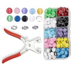 the scissors are next to some buttons and pins in a box with other items nearby