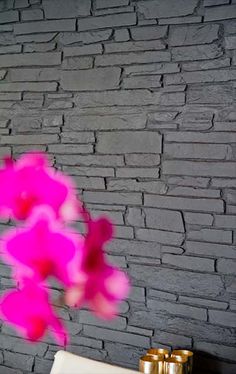 a pink flower in front of a brick wall with candles on the table next to it