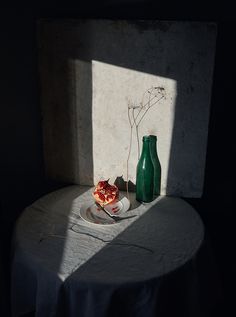 a plate with food on it next to a green vase and some flowers in the shadow