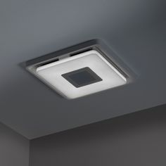 a square light fixture on the ceiling in a room with gray walls and flooring