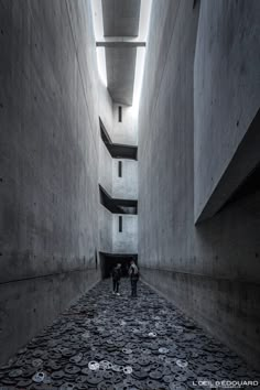 two people are walking down an alley way with stacks of coins on the ground in front of them