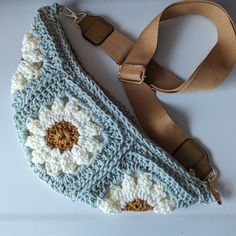 a crocheted purse sitting on top of a white table next to a brown strap