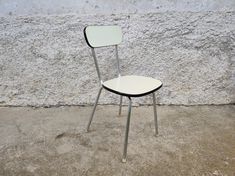 a white and black chair sitting in front of a cement wall with no one on it