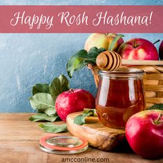 happy rosh hashanah with apples and honey jar on wooden table in front of blue wall