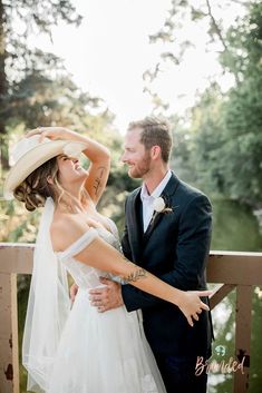 a bride and groom standing on a bridge