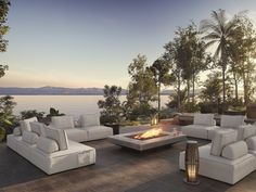 a fire pit sitting on top of a wooden floor next to white couches and chairs