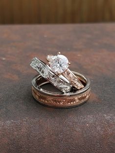 two wedding rings sitting on top of each other with one diamond in the middle,