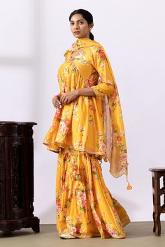 Mustard yellow gathered kurta with floral digital prints and lace detailing. Paired with printed gharara and dupatta.
Components: 3
Pattern: Printed
Type Of Work: Floral
Neckline: V neck
Sleeve Type: Three quarter
Fabric: Chanderi
Color: Yellow
Other Details: 
Lace detailing
Tassel tie-up
Tassel detailing on edge of dupatta
Scallop border
Occasion: Puja - Aza Fashions Yellow Straight Kurta Palazzo Set For Festivals, Festive Yellow Sharara With Straight Kurta, Designer Yellow Sharara With Straight Kurta, Yellow Anarkali Palazzo Set With Straight Kurta, Designer Yellow Dupatta With Dabka, Diwali Semi-stitched Yellow Sharara, Yellow Semi-stitched Sharara With Zari Work, Yellow Sharara With Dabka Straight Kurta, Yellow Sharara With Straight Kurta