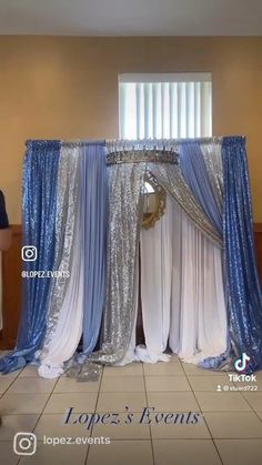 a man standing in front of a blue and white stage with drapes on it