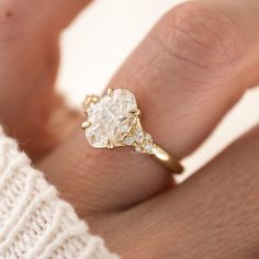 a woman's hand holding a ring with a white diamond in the middle and yellow gold band