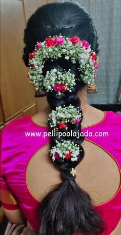 the back of a woman's head with flowers in her hair and an elaborate braid