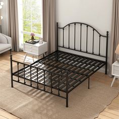 a black metal bed frame sitting on top of a wooden floor next to a window