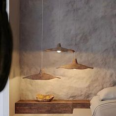 three lamps hanging from the ceiling above a table with food on it and a bed in the background