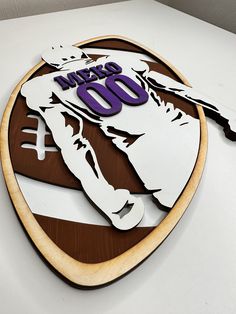 a wooden sign with the name and number of a football player in purple on it