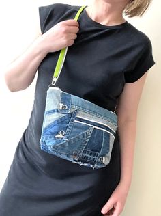 a woman wearing a black shirt and blue jeans holding a green handbag in her pocket